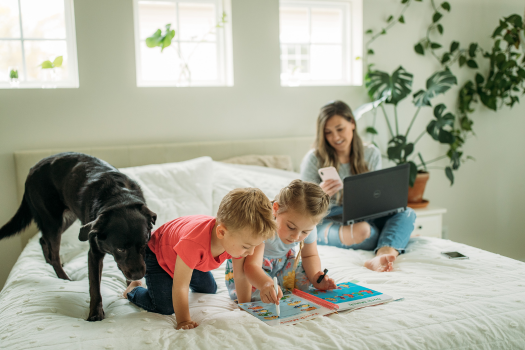 Young woman juggling work two kids and their dog at home