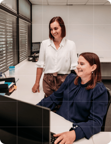 Two Trekk Advisory team members smiling while working together at a desktop, reflecting collaborative business advisory support.