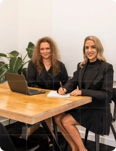 Trekk Advisory team members reviewing documents and smiling during a business advisory meeting at a wooden desk.