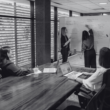 Team of business accountants in Rockhampton in a strategy meeting, brainstorming ideas on a whiteboard to refine a business and cashflow plan for growth.