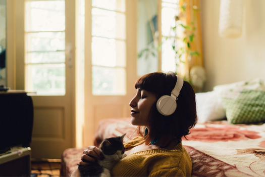 A female entrepreneur listening to music in her bedroom after taking time off during covid-19.