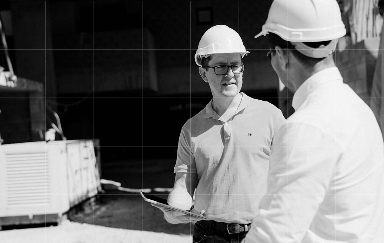 Two Trekk Advisory team members in hard hats talking at a construction site.