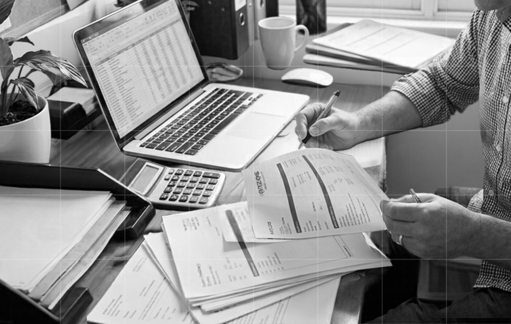 Trekk Advisory team member reviewing printed reports with a pen beside a laptop spreadsheet and calculator