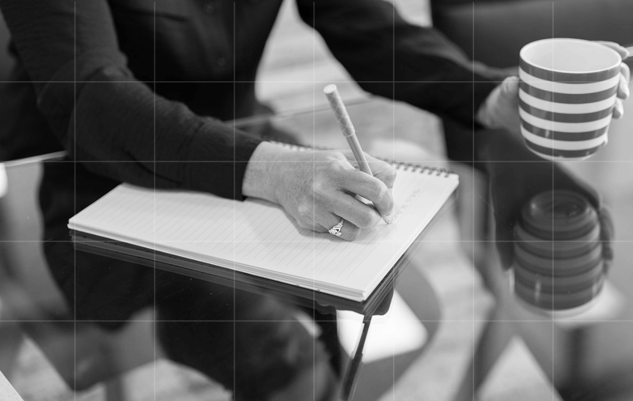 A Trekk Advisory team member writing in a notebook at a desk.