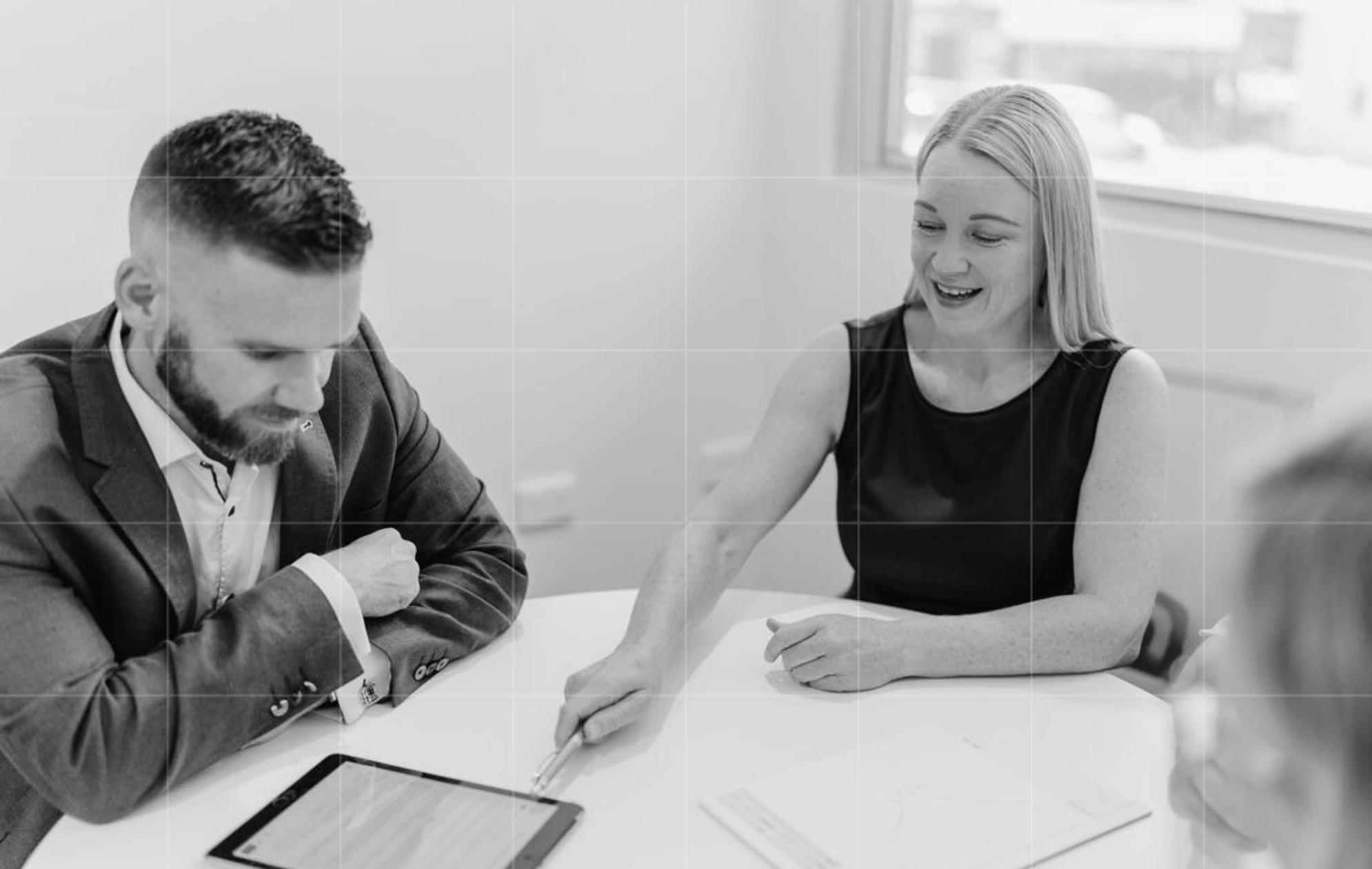 Two Trekk Advisory team members reviewing financial information on a tablet during an internal strategy discussion.