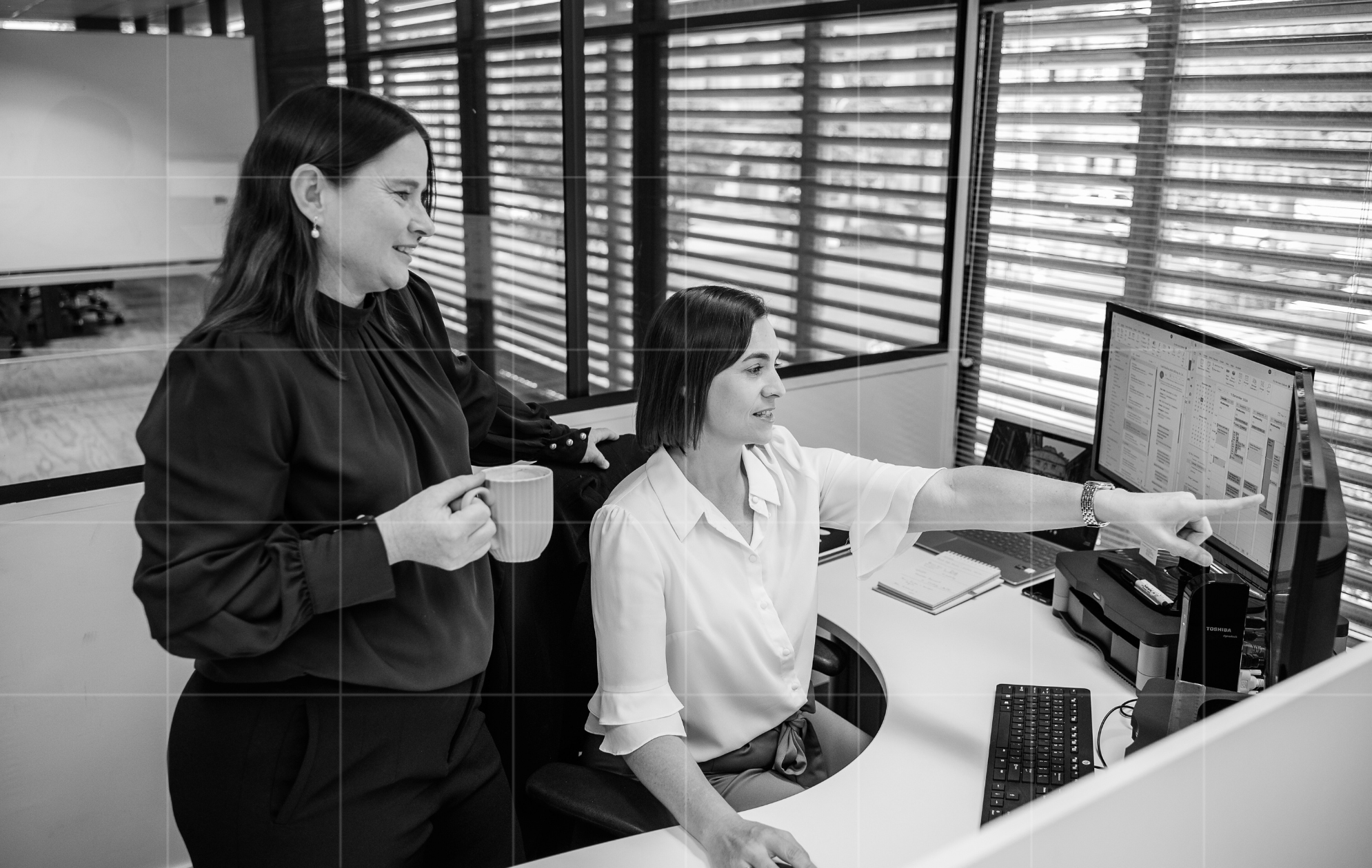 Two professionals reviewing employment compliance on screen, discussing changes to non-compete clauses and business contracts in a modern Australian workplace