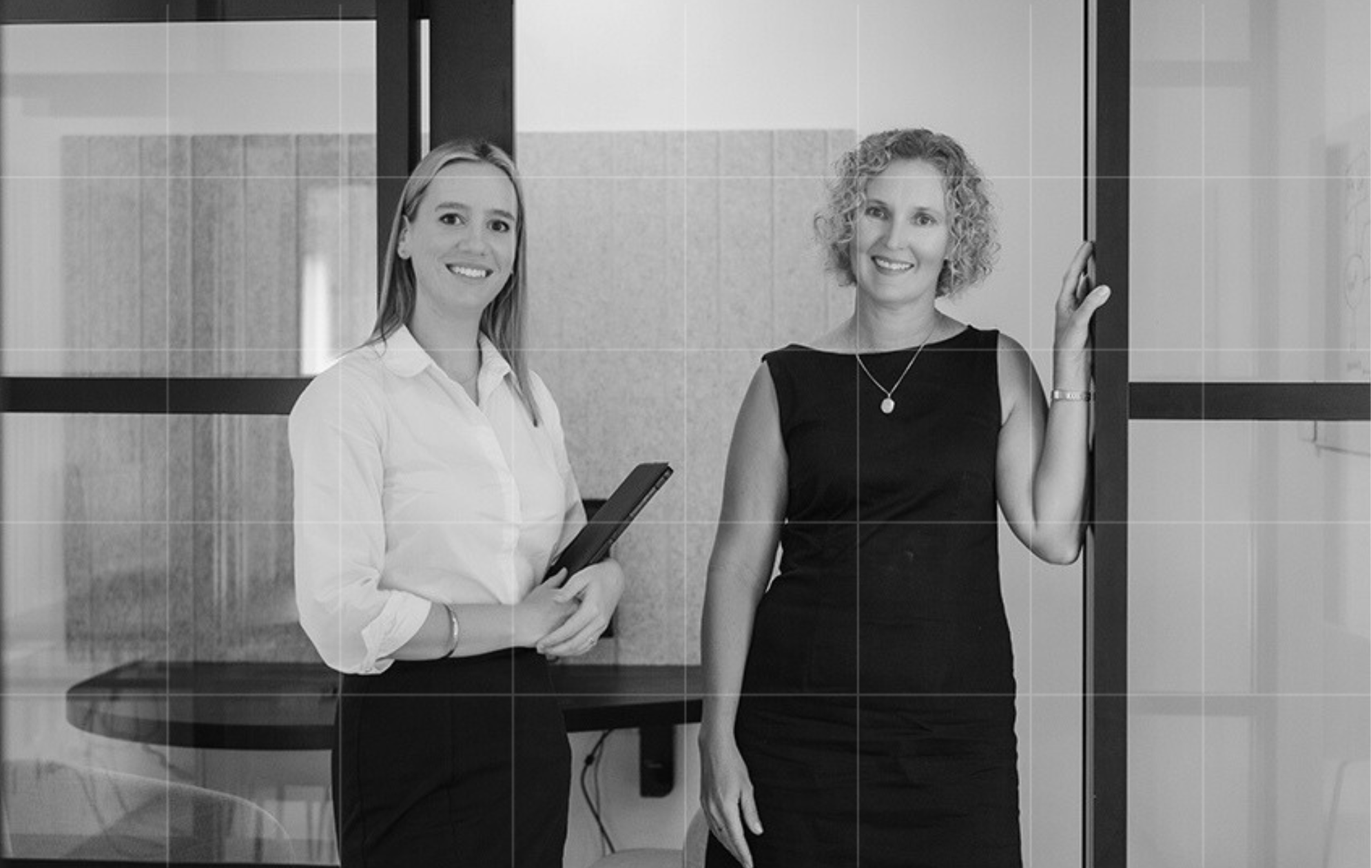 Two business advisory consultants smiling in a meeting room.