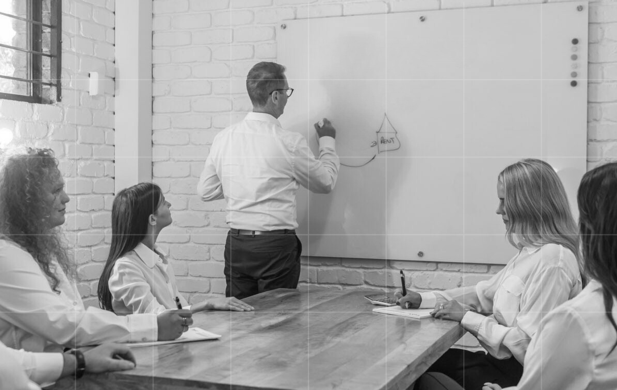Business advisors in a team meeting as a presenter outlines strategy on a whiteboard, showcasing Trekk Advisory’s consultative tax planning.