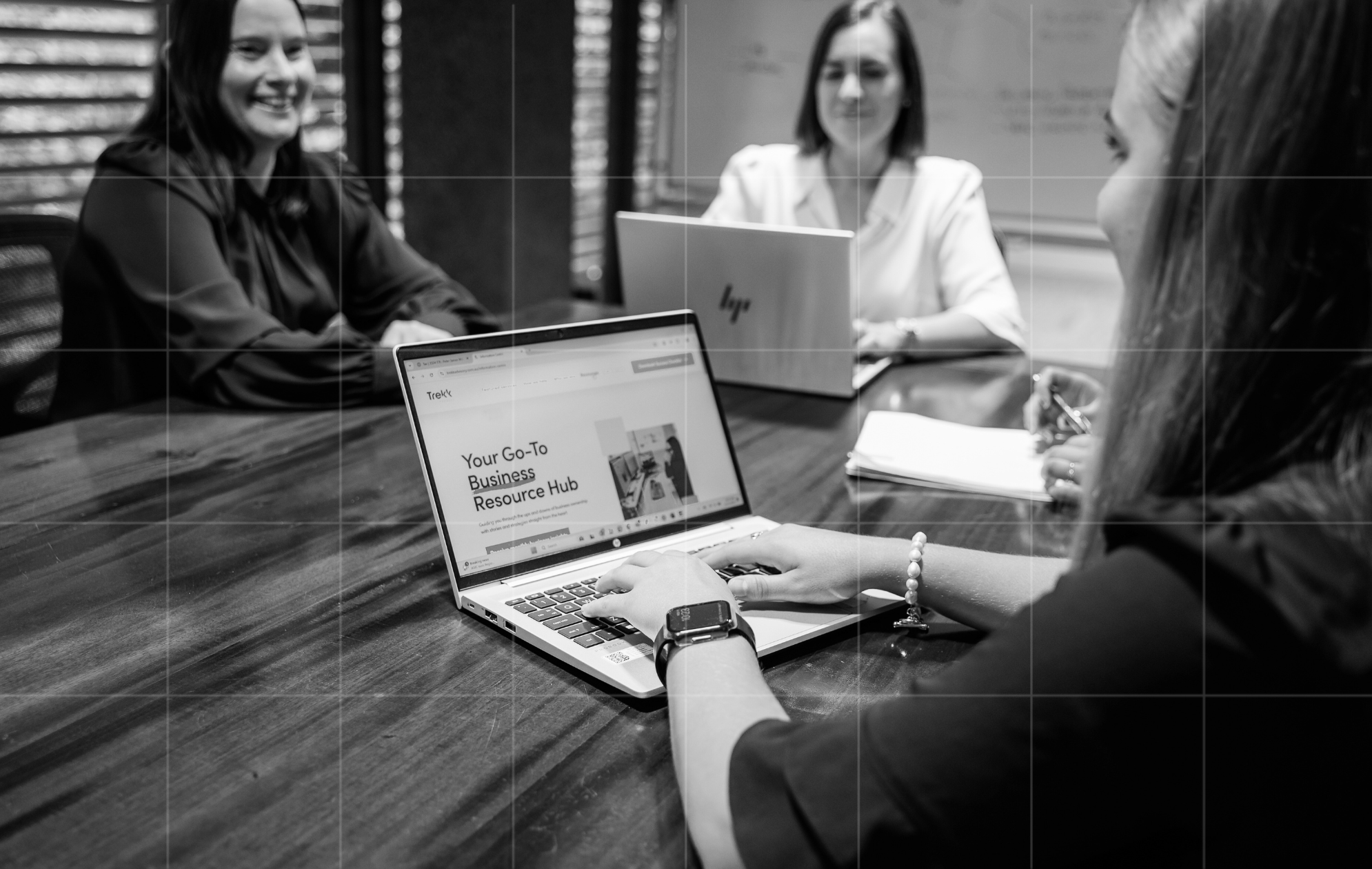 Business advisory team meeting with laptops around a boardroom table.