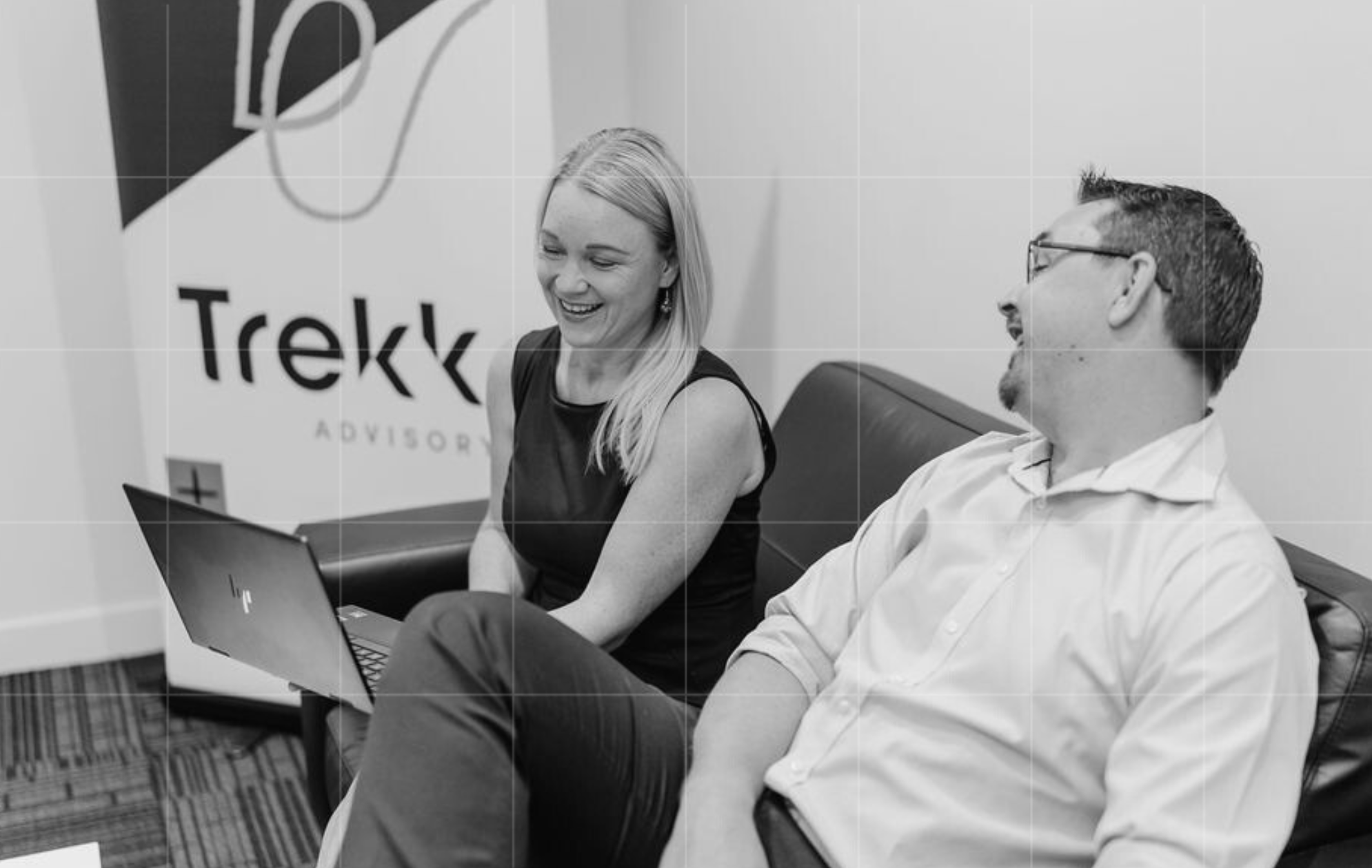 Two professionals smiling during a casual business meeting at Trekk Advisory, discussing small business bookkeeping support services.