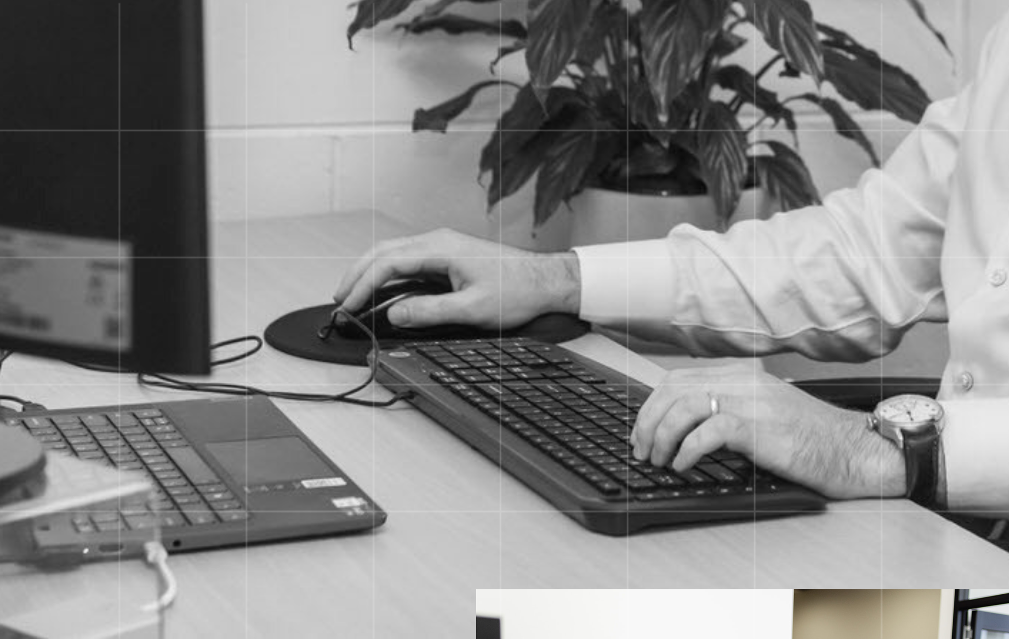 Close-up of hands typing on a keyboard at a desk with a laptop nearby.