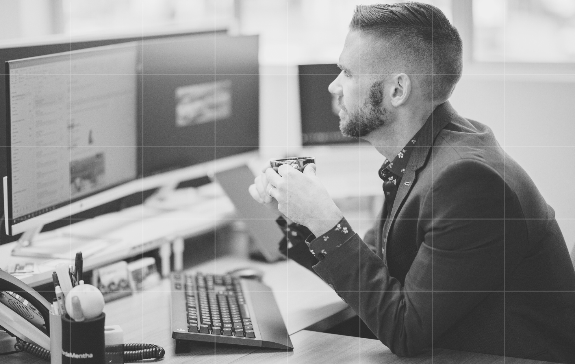 Business advisor reviewing financial data and reports on dual monitors, showing focus on business advisory and cash flow planning.