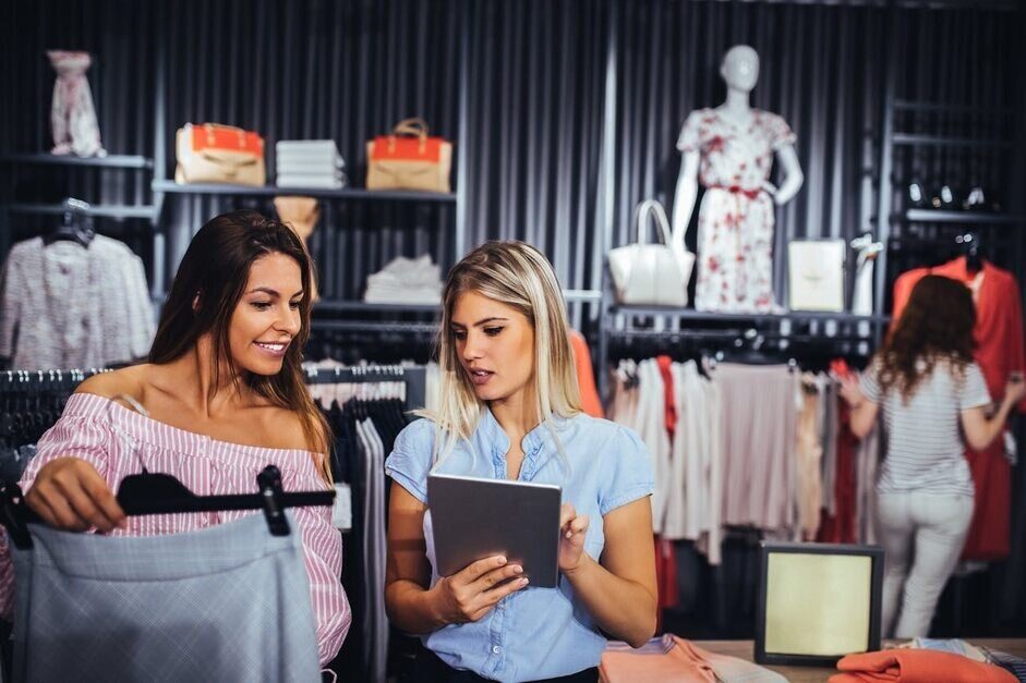 Two women in retail store working with new e commerce technology.
